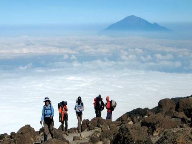       Group of hikers trekking above clouds.
  