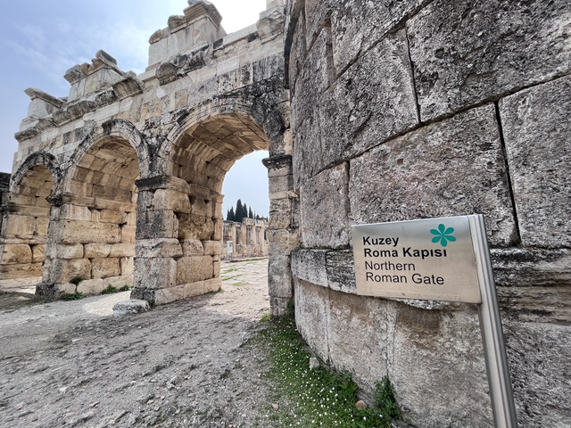 Ancient Roman gate with a sign in the foreground.
