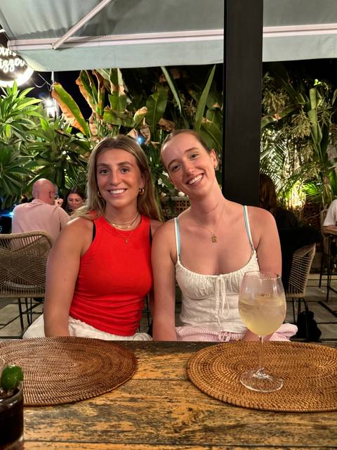 Two women sitting at a table with a drink.