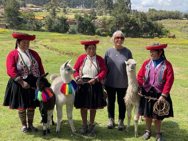       Women in traditional clothing with alpacas in a rural setting.
  