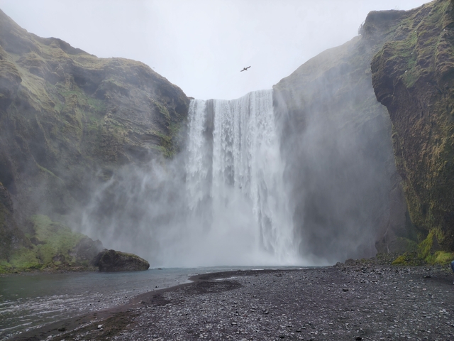 Waterfall cascading down rocky cliffs with mist in the air.