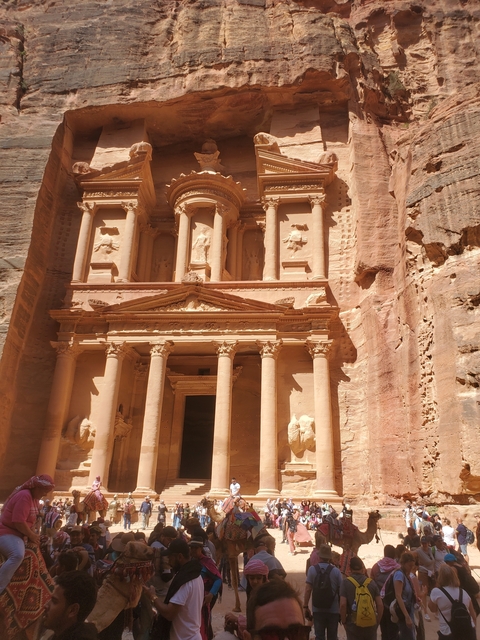 Iconic facade of the Al Khazneh in Petra carved into red stone.