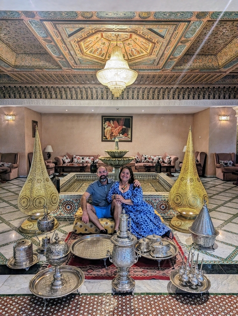       A couple sits in a lavish room with traditional Moroccan decor.
  