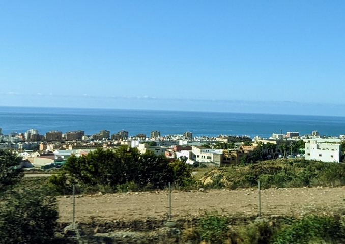       View of a city with buildings and a view of the sea.
  