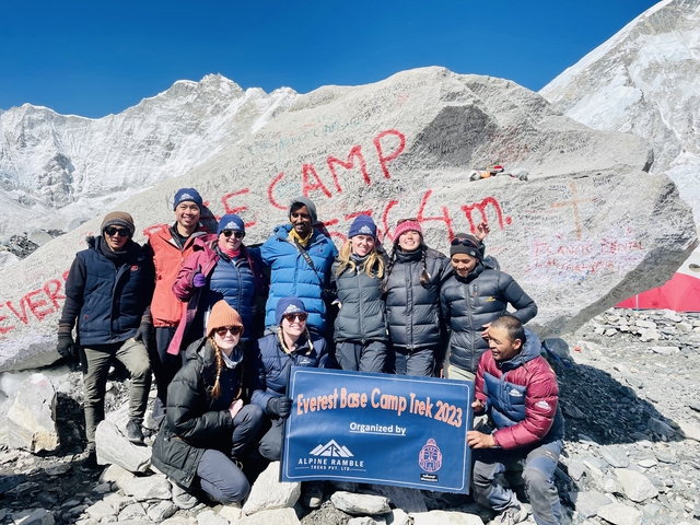 Group photo at Everest Base Camp with stone marker.