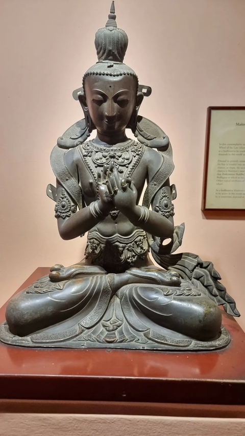       Intricate metal statue in a meditative pose in a museum.
  