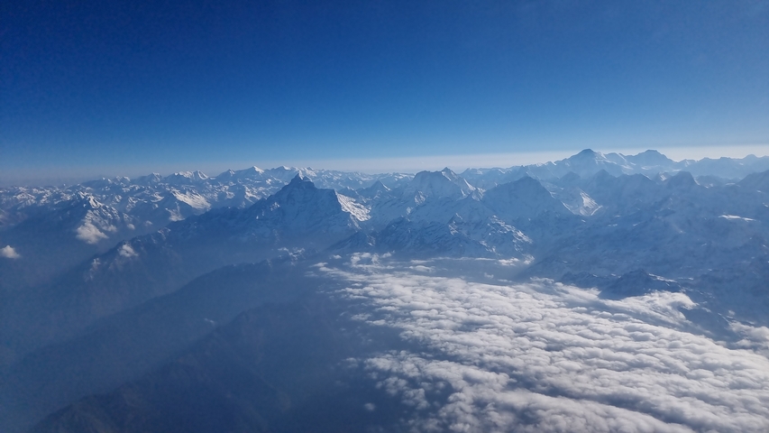 Panoramic view of snow-covered mountain range with clouds.