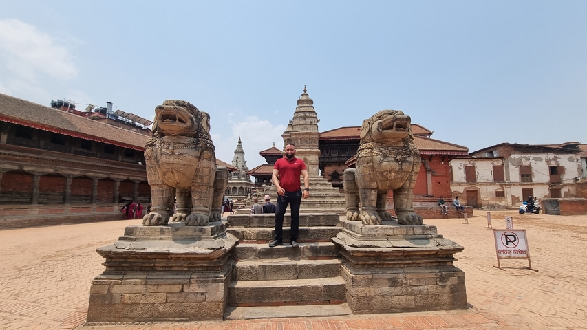       Person standing between two large statues at a historic site.
  