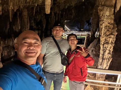 Two people smiling inside a cave with stalactites.