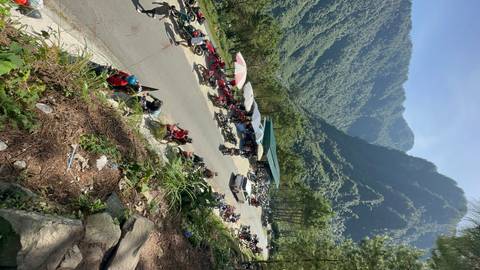 View of a mountain landscape with a road lined with umbrellas and stalls.