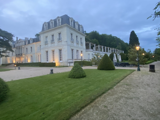 Large white mansion with a manicured garden at dusk.