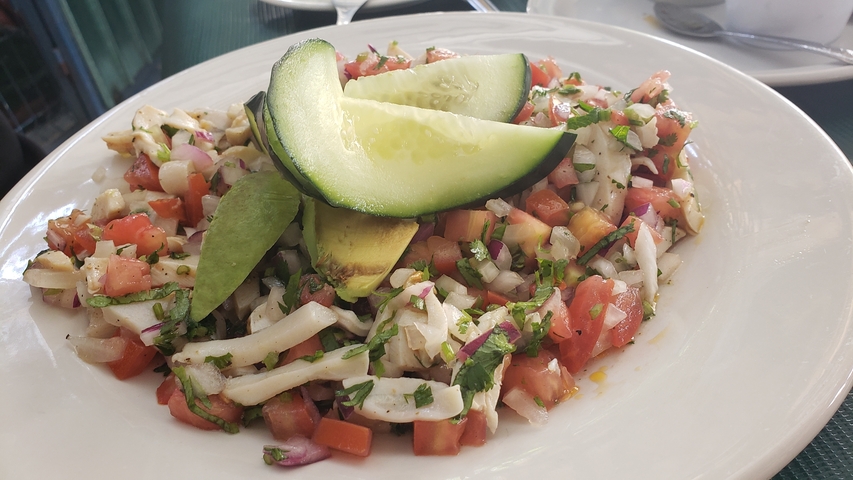 Fresh salad with tomatoes and avocado on a white plate.