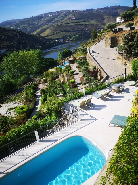 Manicured garden terrace with sun loungers and views of a river.
