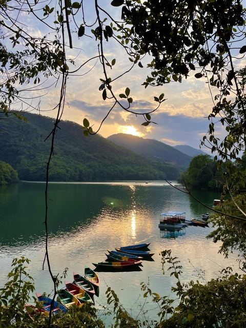 A calm lake at sunset with mountains in the background.