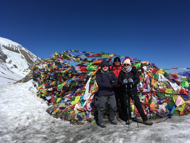 Group of people at a high mountain pass with colorful prayer flags.