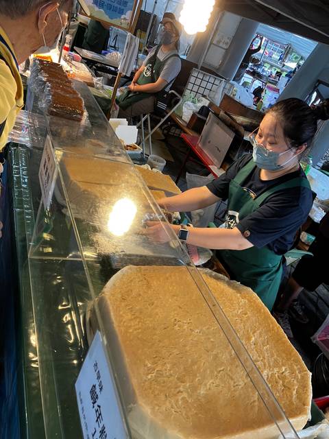 Market stall with food items displayed behind glass.