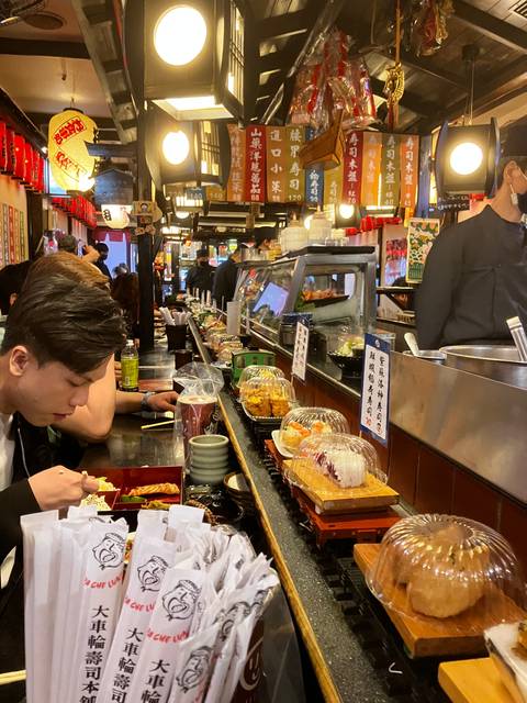       Busy market scene with signs and food displays.
  