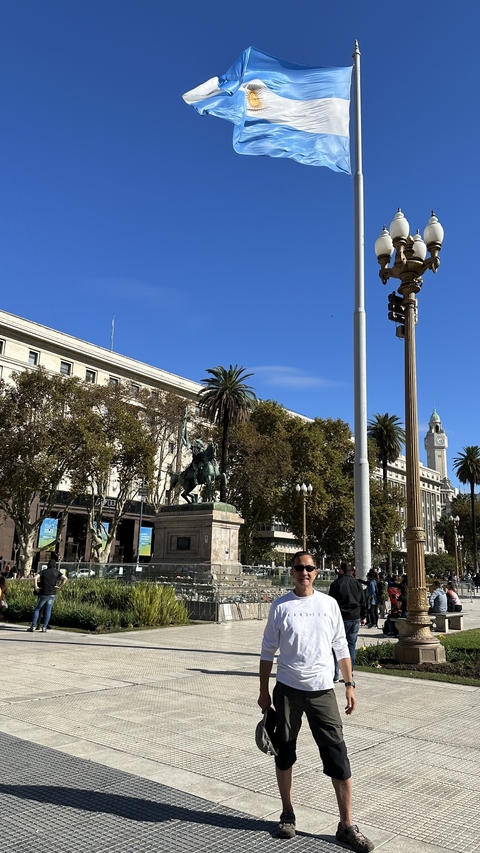 Statue in a plaza with historical buildings and palm trees.
