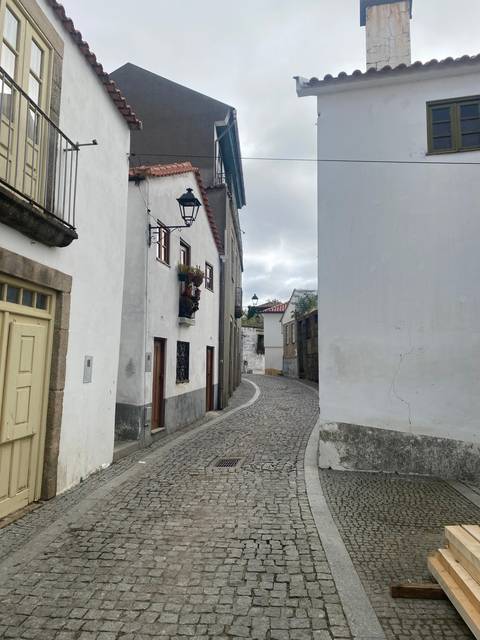 Narrow cobblestone street with white buildings.