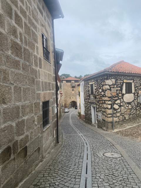 Cobbled street with stone buildings and cloudy sky.