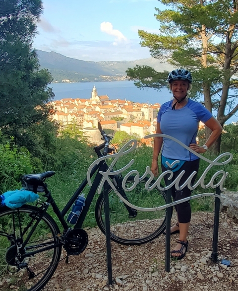 Person with a bicycle overlooking a town in the distance.