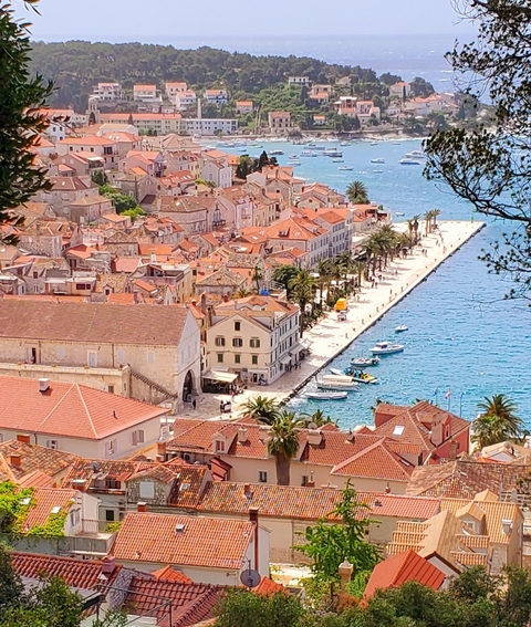 Aerial view of a coastal town with red roofs and clear blue waters.