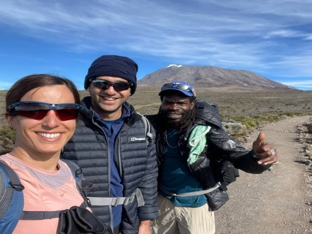 Three people posing with a mountain in the background.