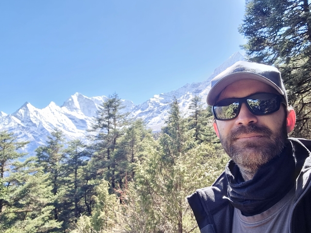 Man posing in front of a mountain range.