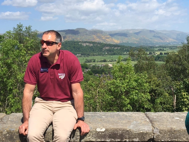 Person sitting on a wall with a scenic landscape in the background.