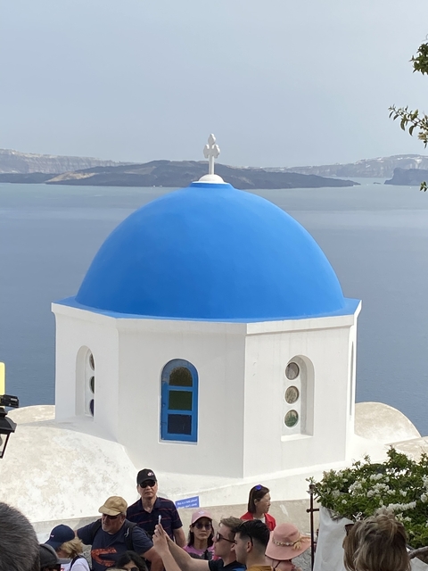       Close-up of a blue-domed church with a sea view.
  