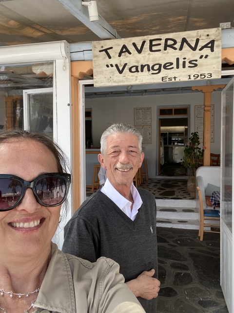       Two people smiling in front of a cafe.
  