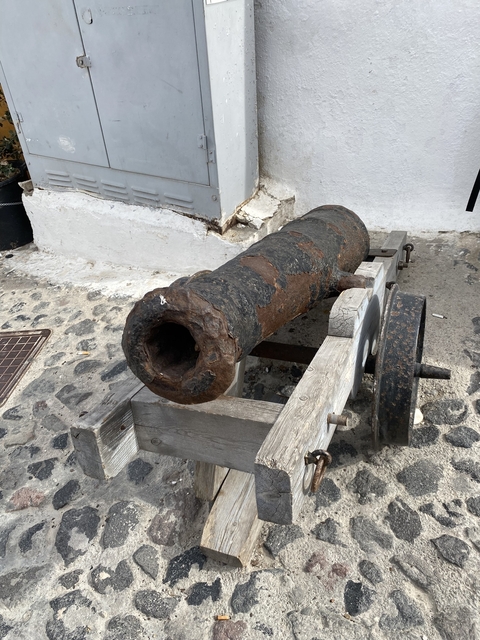       Old cannon displayed on cobblestone platform.
  