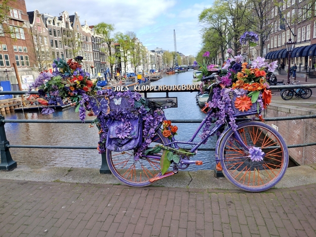       Bicycle decorated with flowers on a canal bridge.
  