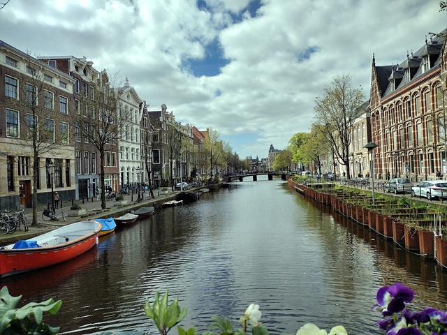       Scenic canal in Amsterdam with boats and historic buildings.
  