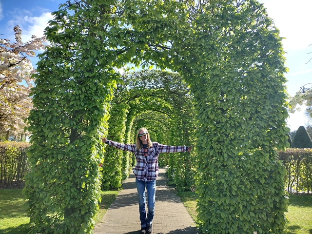       Smiling person posing in a garden archway.
  