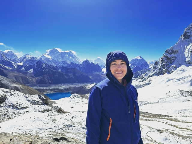 Woman in winter clothing smiling with mountains in the background