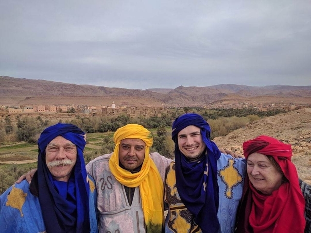       Group of people in colorful traditional clothing with desert landscape
  