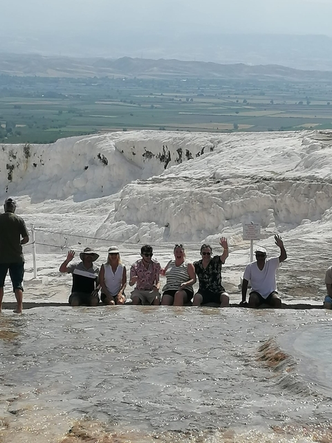       A group of people posing in front of the travertines at Pamukkale.
  