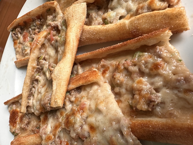 Close-up of Turkish pide, a traditional dish with toppings on a wooden board.