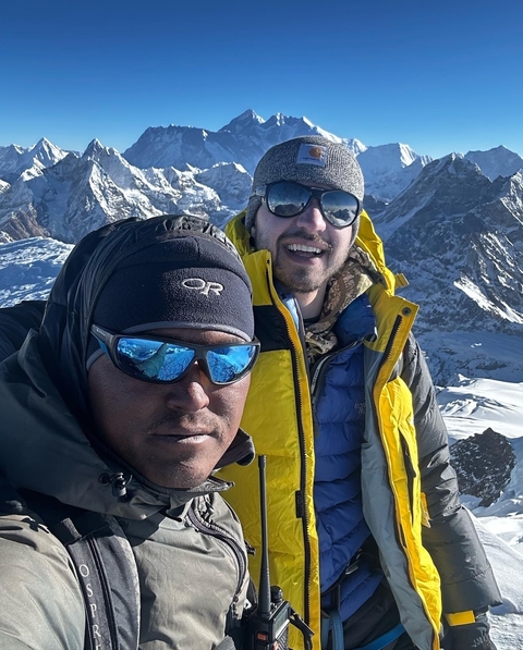 Two men smiling in snow-covered mountain area.