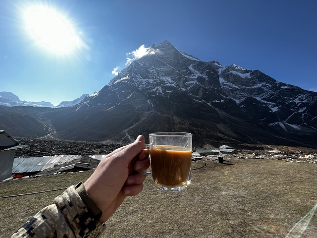 Hand holding a cup with mountain backdrop.