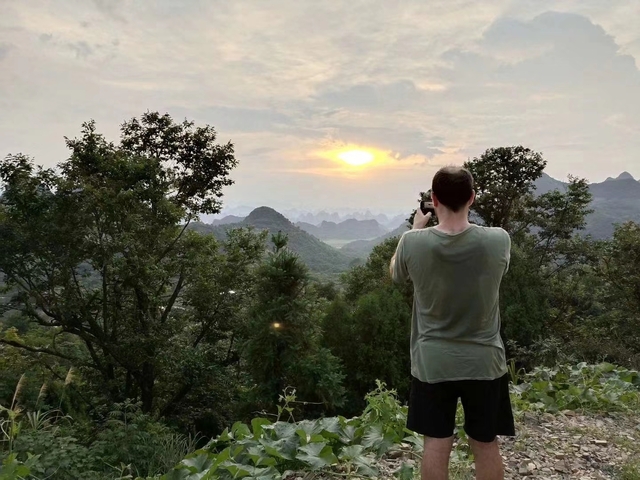 Person capturing a sunset over mountainous terrain.