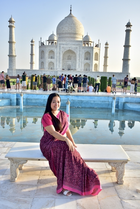       A woman in traditional attire with the Taj Mahal in the background.
  