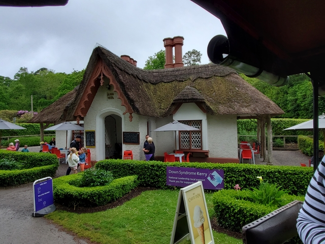 A quaint building with a thatched roof surrounded by greenery.