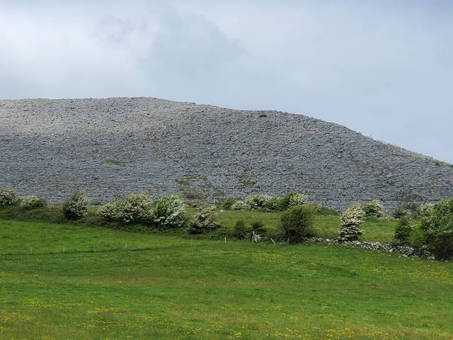 A hilly landscape with green fields and cloudy skies.
