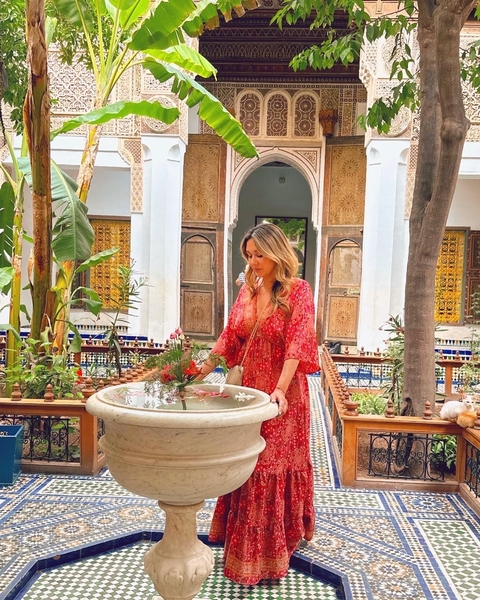 Woman standing by a fountain in a traditional courtyard.