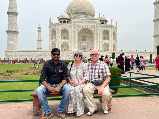 Two people sitting with a guide at the Taj Mahal.