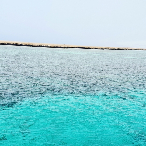       Clear waters with a rocky coastline in the distance.
  