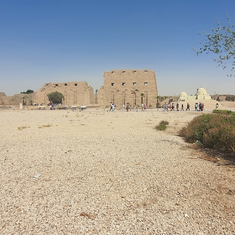       People touring an ancient archaeological site with large stone buildings.
  