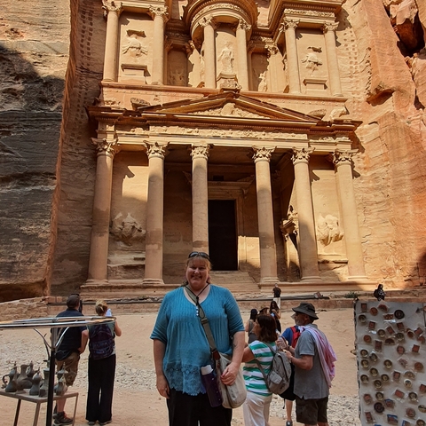 A woman standing in front of the Petra Treasury with carved stone façade.